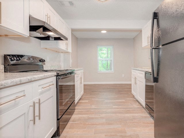 A kitchen with white cabinets and a black refrigerator.