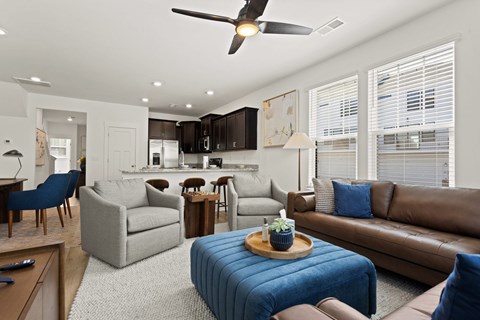 A living room with a brown leather couch and a blue ottoman.