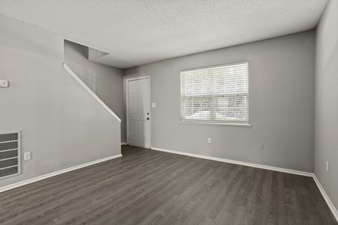 A room with a staircase and a window with blinds.