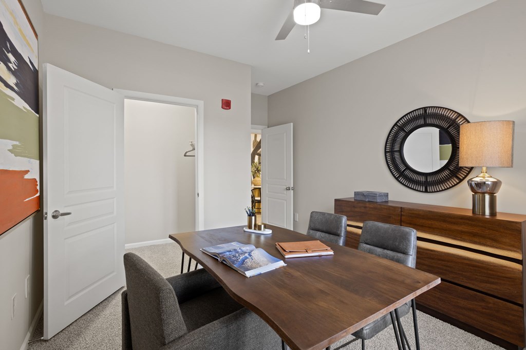 Flatiron West Trade Apartments staged model unit home office with gray carpet and dark wood furniture