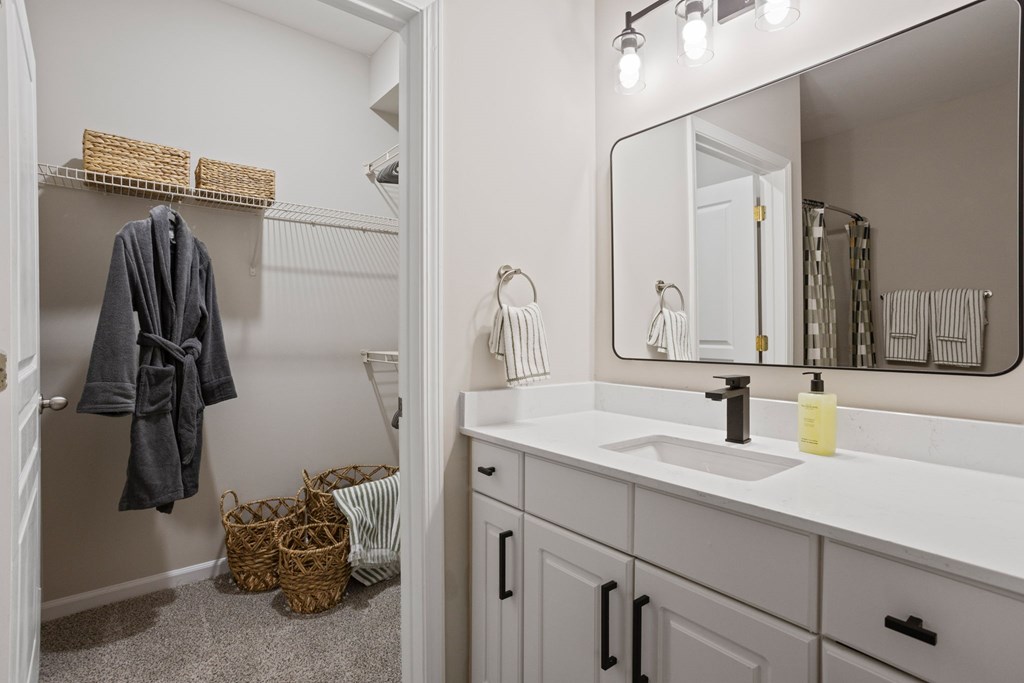 Flatiron West Trade Apartments staged model unit bathroom with a quartz countertop and attached walk-in closet