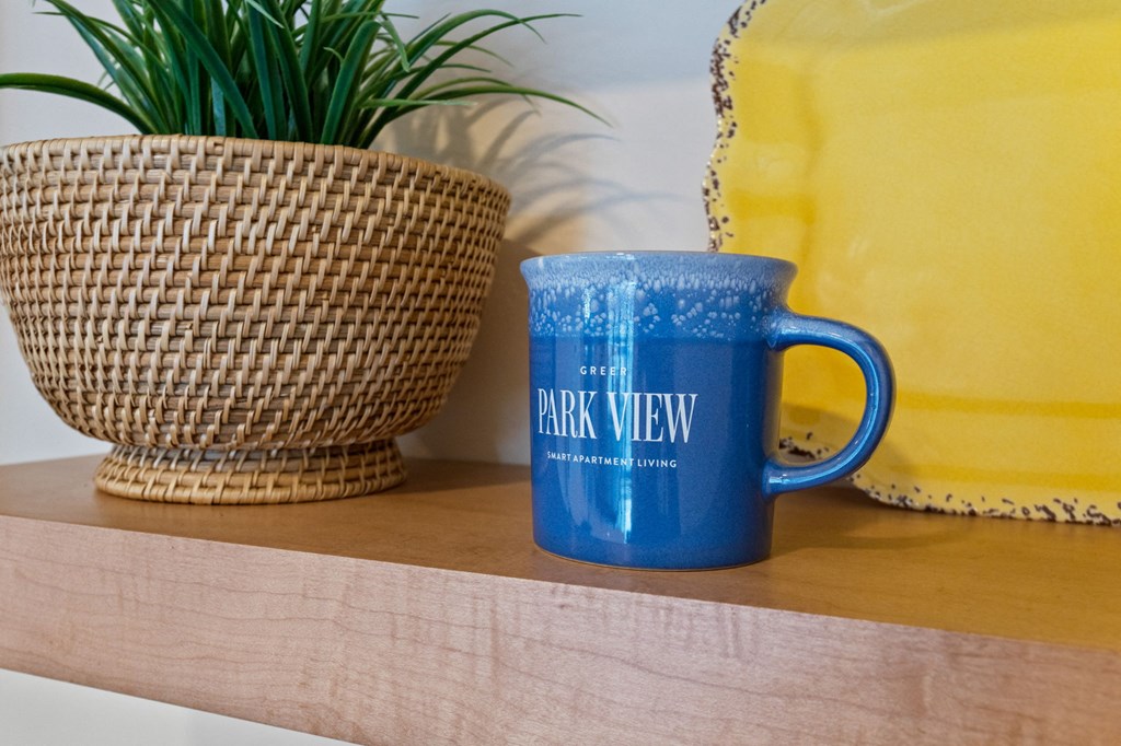 Blue coffee mug with Park View Greer Apartments written on it in white