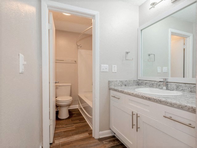 A white bathroom with a toilet, sink, and mirror.