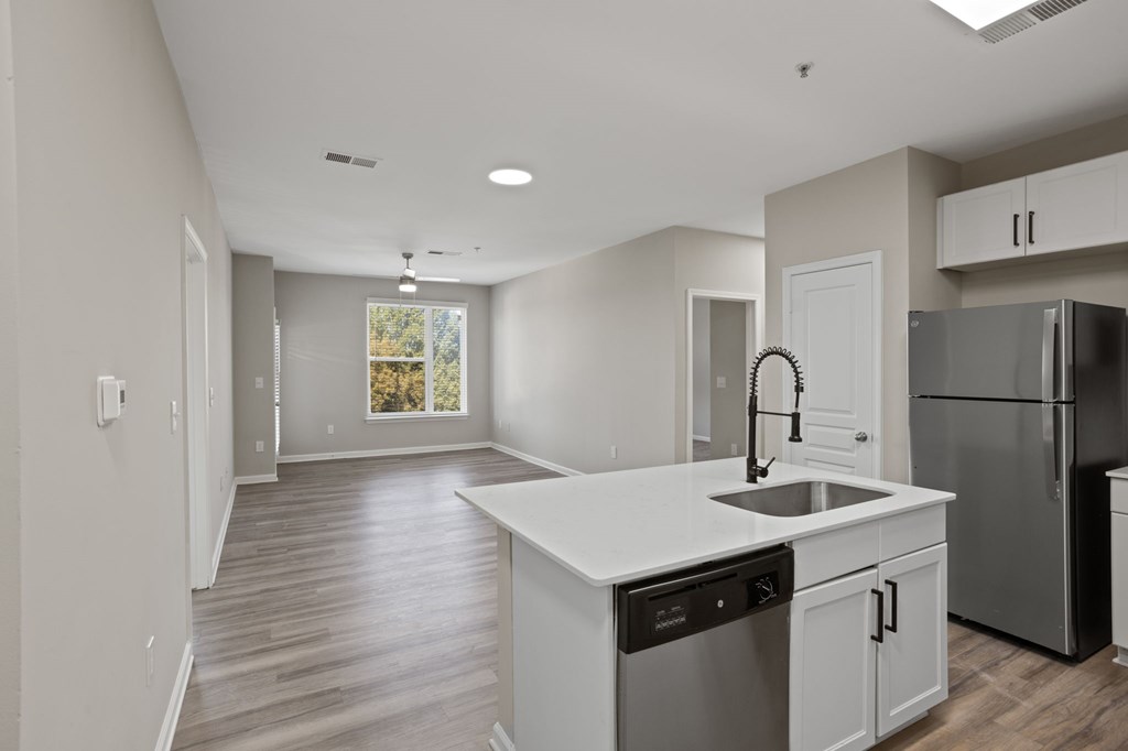 Flatiron West Trade Apartments unstaged model unit with quartz countertops, stainless steel appliances and a large living room.