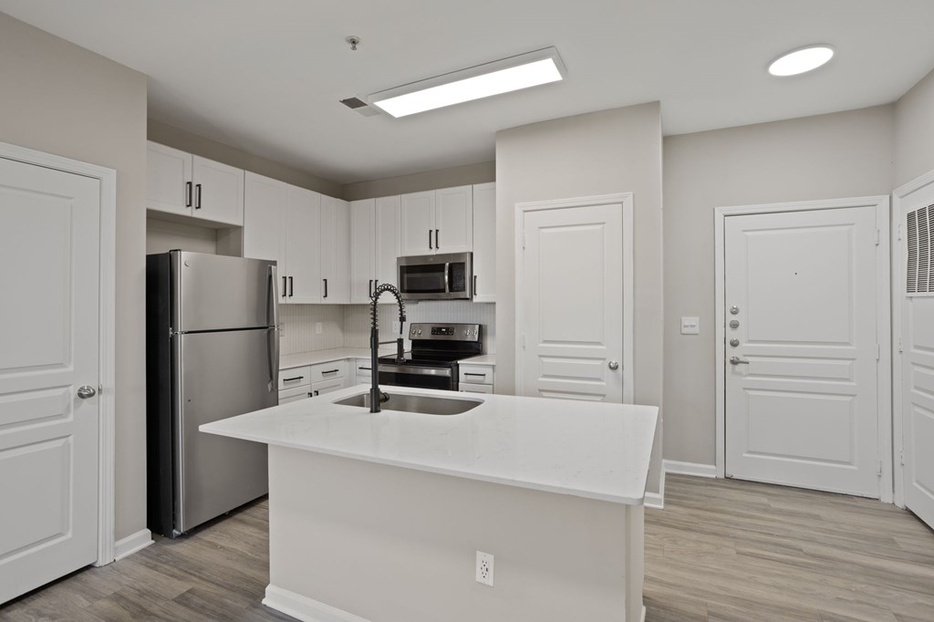 Flatiron West Trade Apartments unstaged model unit with quartz countertops, stainless steel appliances and a large living room.