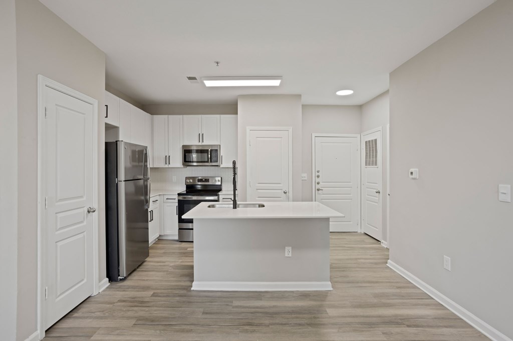 Flatiron West Trade Apartments unstaged model unit with quartz countertops, island, stainless steel appliances and a large living room.