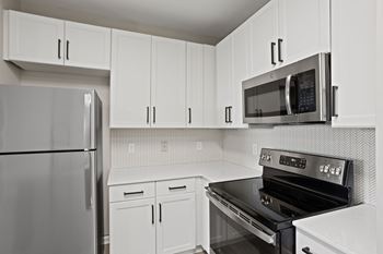 A kitchen with white cabinets and a black stove top oven.