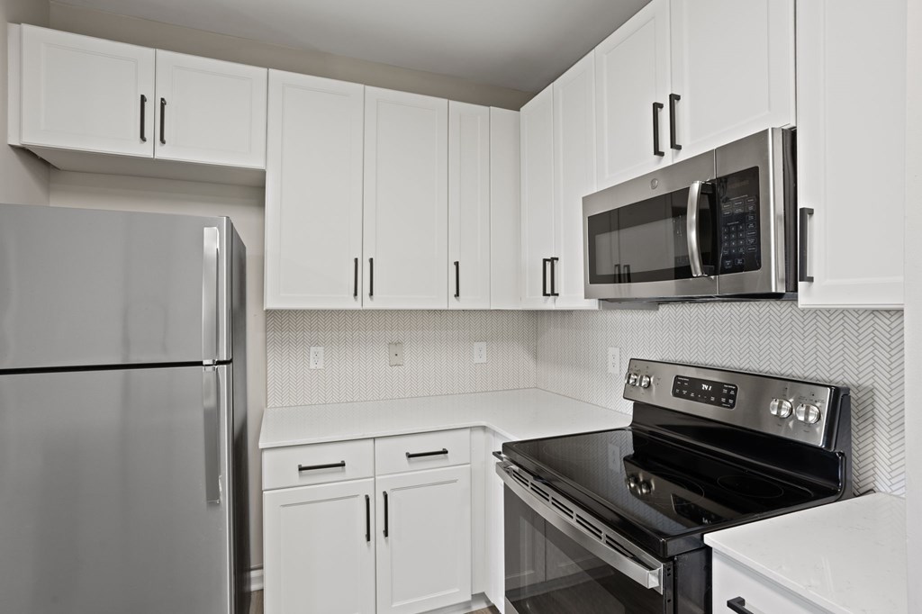 Flatiron West Trade Apartments staged model unit kitchen connected to living room with stainless steel modern appliances and quartz countertops