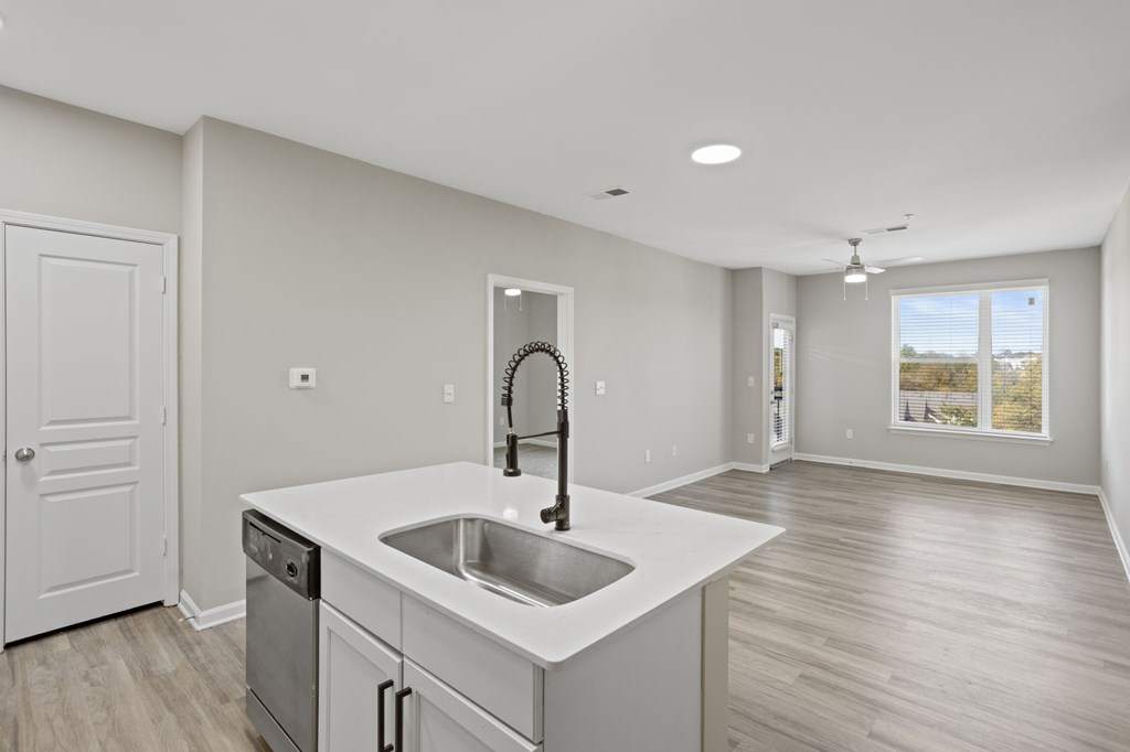 Flatiron West Trade Apartments unstaged model unit with quartz countertops, stainless steel appliances and a large living room.