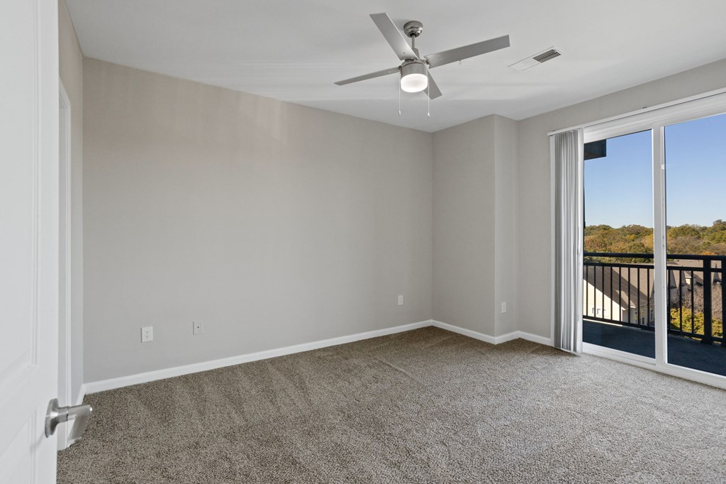 Flatiron West Trade Apartments gray carpeted bedroom with attached balcony