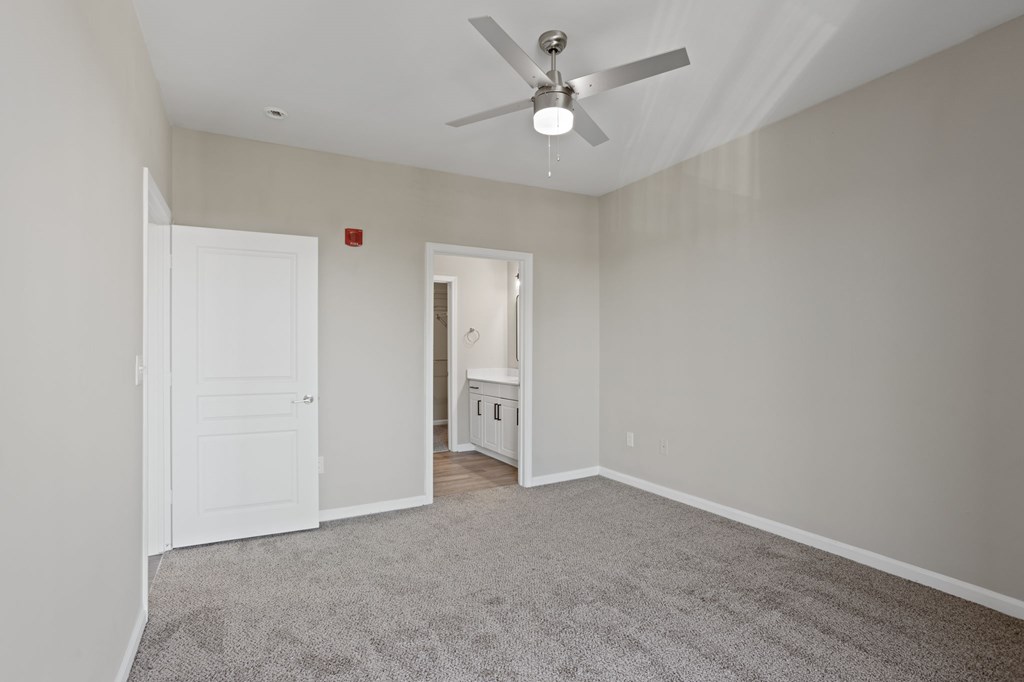 Flatiron West Trade Apartments gray carpeted bedroom with attached bathroom and walk-in closet