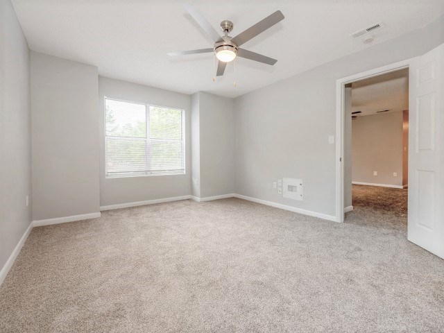 A room with a ceiling fan and carpeted floor.