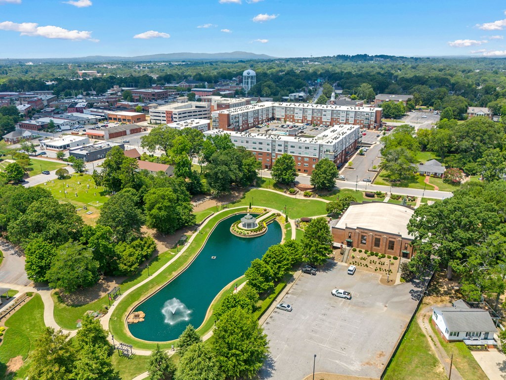 A large building complex with a fountain in the middle of a green area.