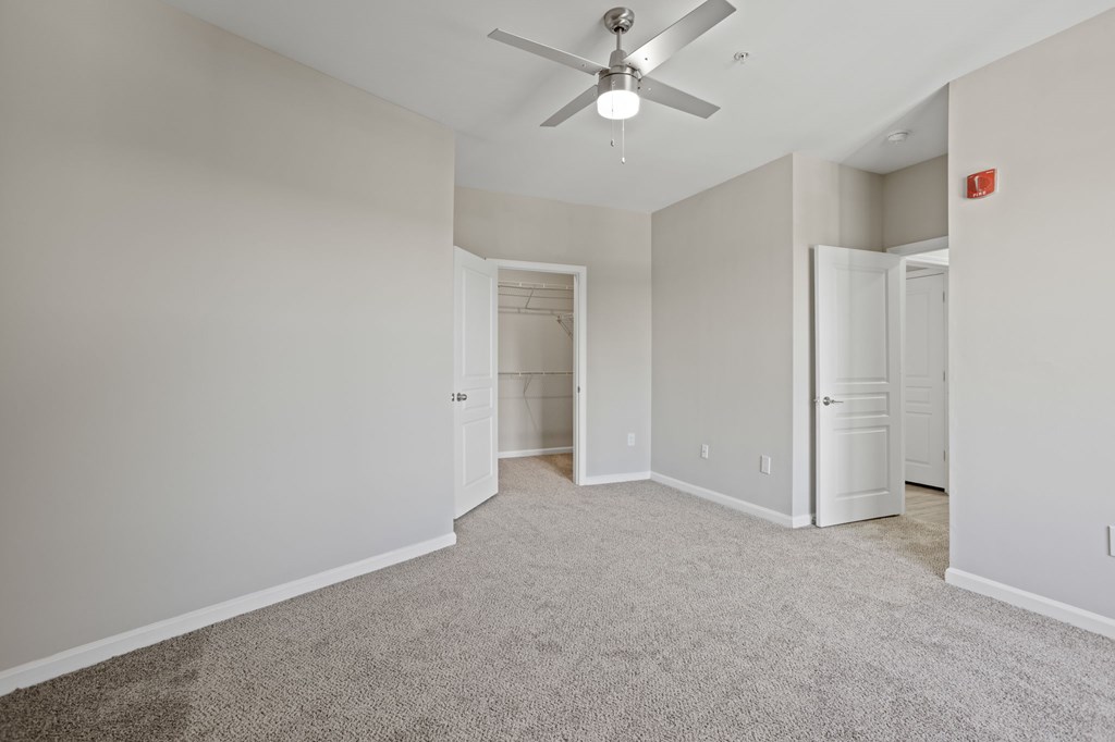 Flatiron West Trade Apartments gray carpeted bedroom with attached balcony