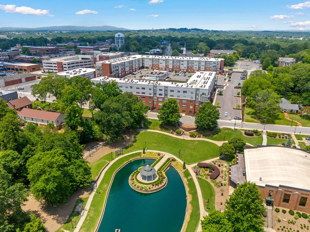 A large building complex with a fountain in the middle of a green area.