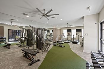 A spacious gym with a variety of equipment and a green exercise mat.