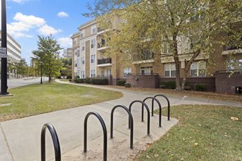 A row of black bicycle racks are in front of apartment buildings.