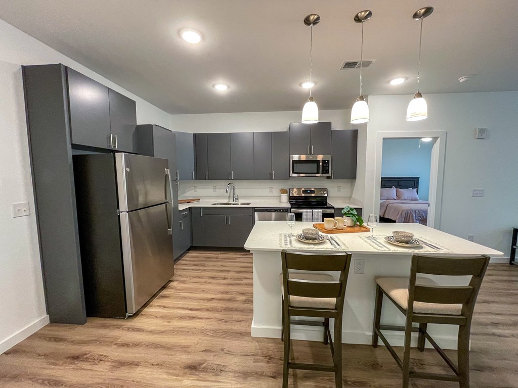 Greenville, SC, Pet-Friendly Apartments - Alston - Kitchen with Stainless Steel Appliances, Barstools, and Quartz Countertops.