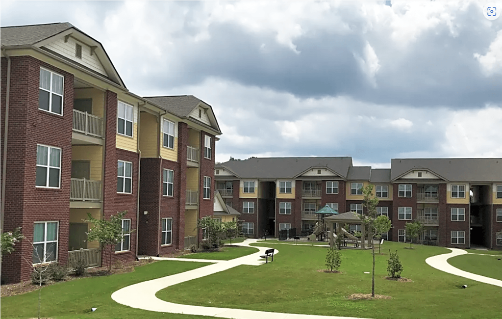 an exterior view of an apartment complex with a green yard