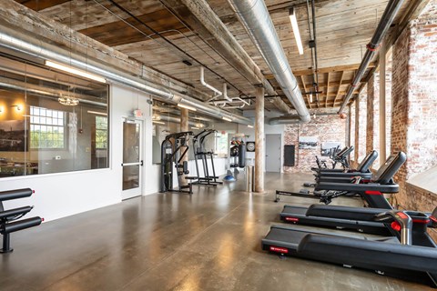 24-Hour Fitness Center in Converse Mill Lofts Apartments in Spartanburg SC, featuring treadmills, stationary bikes, ellipticals, and free weights