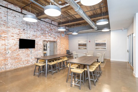 Converse Mill Lofts Apartments Community Room with tables, chairs and a TV