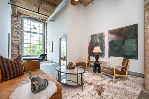 A living room with a brown leather couch and a glass coffee table.