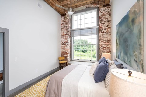 Converse Mill Lofts Luxury Apartments Model Unit Staged Bedroom with high ceilings, exposed beams