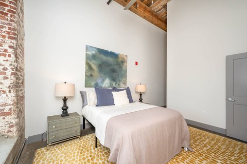 Converse Mill Lofts Luxury Apartments Model Unit Staged Bedroom with high ceilings, exposed beams