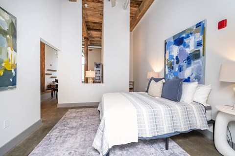 Converse Mill Lofts Luxury Apartments Model Unit Staged Bedroom with high ceilings, exposed beams