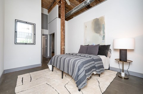 Converse Mill Lofts Luxury Apartments Model Unit Staged Bedroom with high ceilings, exposed beams