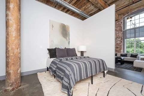 Converse Mill Lofts Luxury Apartments Model Unit Staged Bedroom with high ceilings, exposed beams