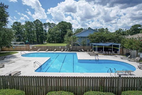 A large blue swimming pool surrounded by a wooden fence.