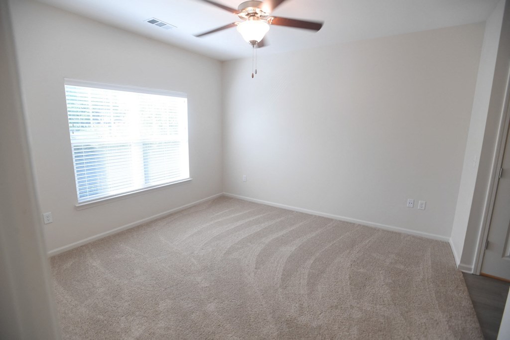 A room with a ceiling fan and a window with blinds.