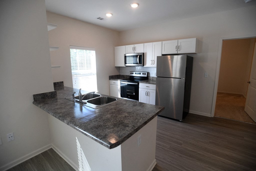 A kitchen with a granite countertop and stainless steel appliances.
