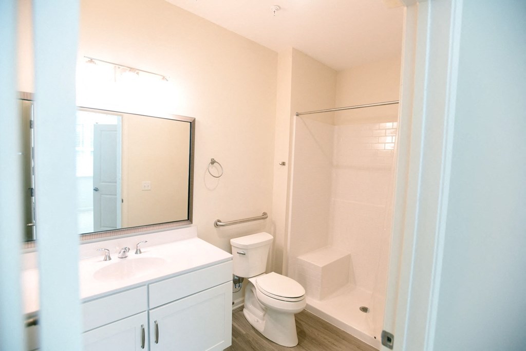 A white bathroom with a toilet, sink, and mirror.