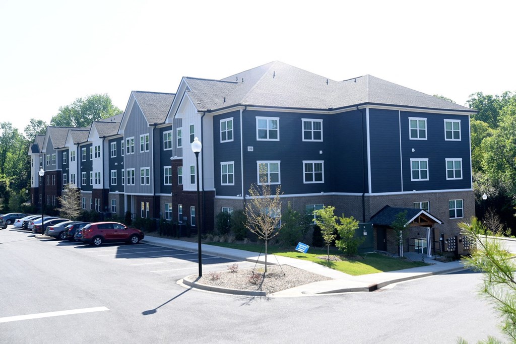 A large apartment complex with a parking lot in front.