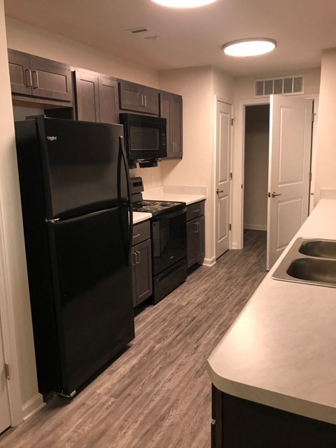 a kitchen with black appliances and white counters and wood floors
