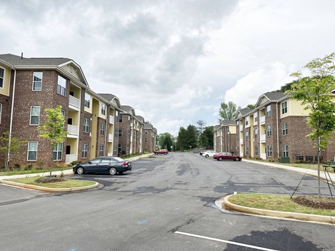 Creekside Village Apartments Exterior, with two buildings facing each other across a large parking lot and a few cars.