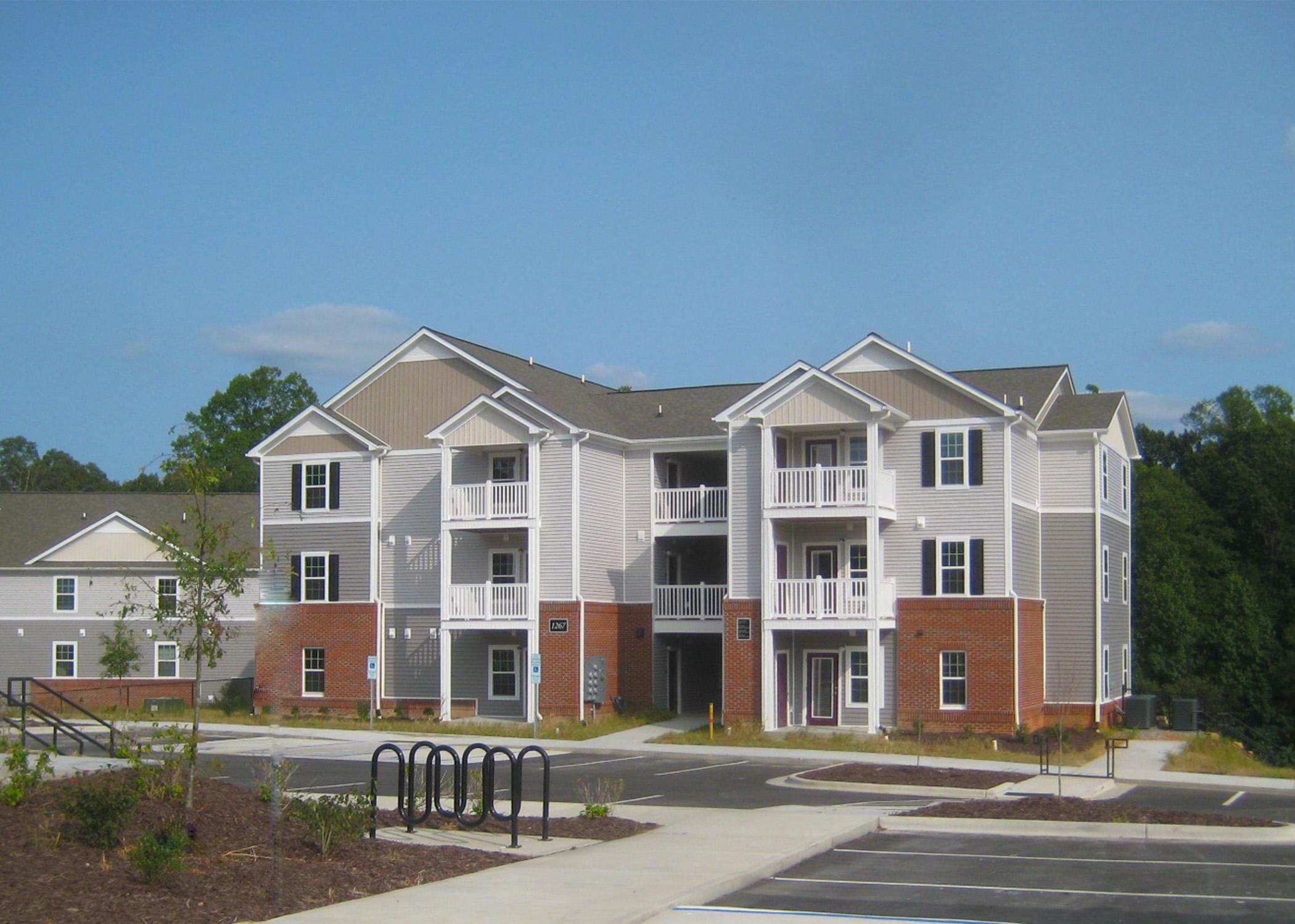 A large apartment complex with a parking lot in front.