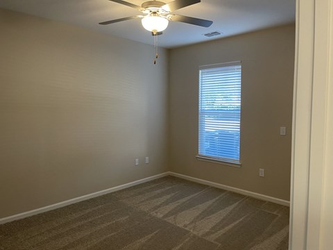 A room with a ceiling fan and a window with blinds.