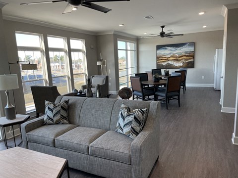 A living room with a grey couch and a painting on the wall.