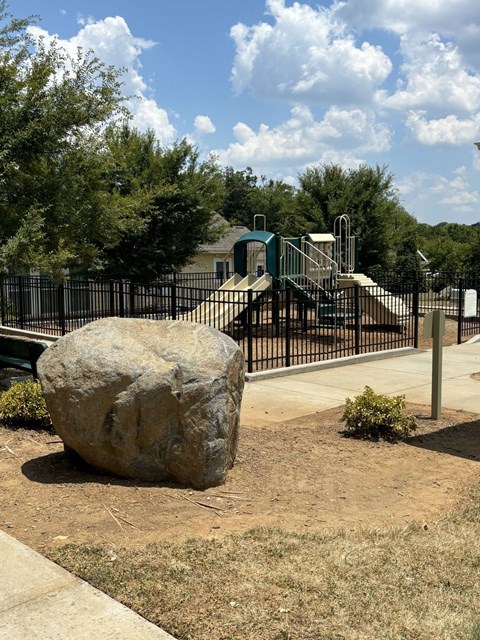 A large rock sits in the middle of a playground.