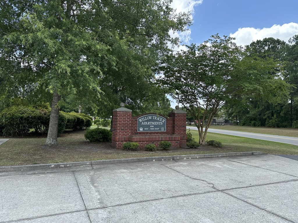 a sign on a brick wall in front of some trees