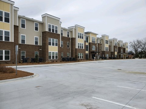 Apartment complex with a parking lot in front.
