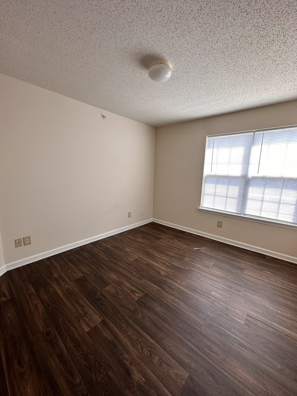 A room with wooden flooring and a window.