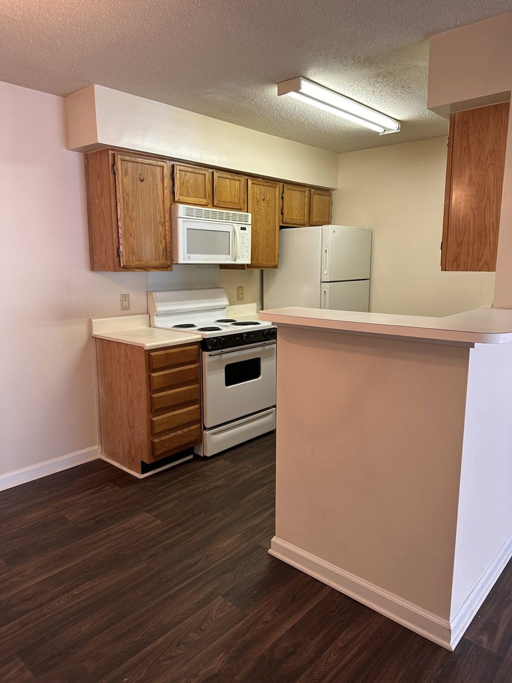 A kitchen with a white microwave above a white stove.