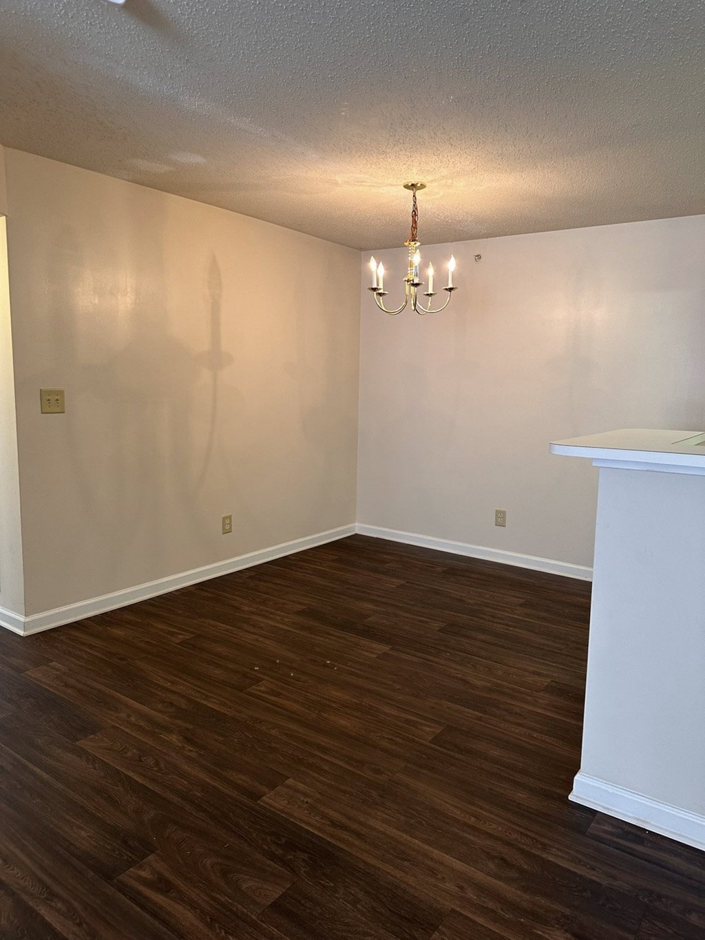 A room with a chandelier and a white fireplace.