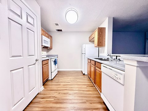 A kitchen with white cabinets and a wooden floor.
