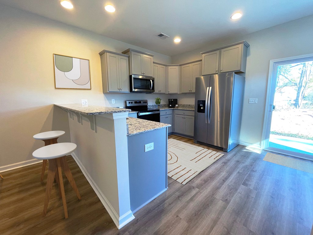 a kitchen with stainless steel appliances and a bar with two stools