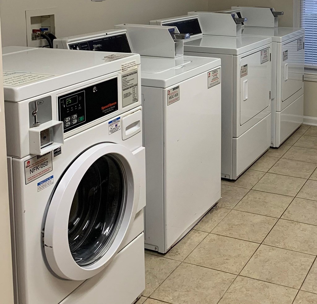A row of white front load washing machines in a laundromat.